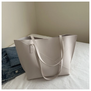 Close-up of minimalist cream tote bag featuring distinctive V-shaped cross stitching