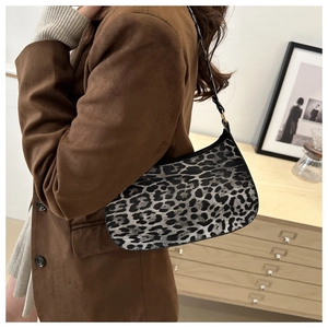 Détail du sac à bandoulière léopard porté avec un blazer marron dans un décor cosy