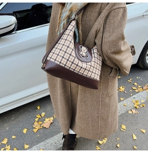 Detail of checkered canvas tote bag with brown leather trim and cute bear embroidery patch