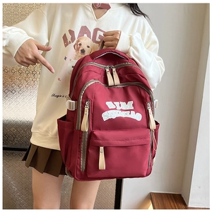 Close-up of burgundy nylon backpack with SIMIAO logo and adjustable side buckles