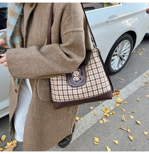 Detail shot of vintage plaid tote bag with cartoon bear embroidery in a warm autumn setting