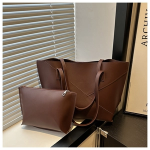 Detail of minimalist tote and pouch set in dark brown leather with V-shaped stitching detail