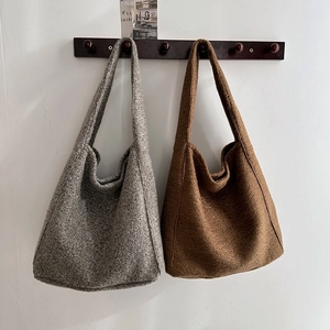 Detailansicht grauer und kaffeebrauner Bouclé-Woll-Tote-Bags an Holzhaken