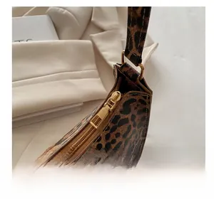 Close-up of smooth golden metal zipper detail on stylish leopard print underarm handbag