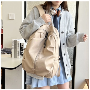 Detail of a beige waterproof backpack with unique pleated texture and slanted front zipper