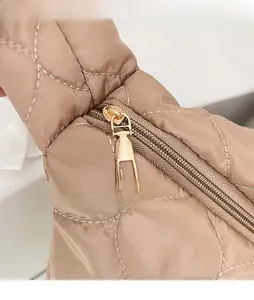 Dettaglio della cerniera in metallo dorato sulla borsa shopper trapuntata color champagne