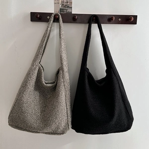 Detail von Woll-Hobo-Taschen in Schwarz und Dunkelgrau an einem Holzbügel hängend