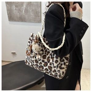 Dettaglio borsa tote in peluche leopardata con tracolla intrecciata e ciondolo a gatto