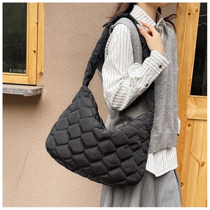 Dettaglio di una grande borsa tote nera trapuntata indossata da una modella casual