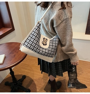Detail view of plaid canvas tote with cute bear patch and off-white leather bottom