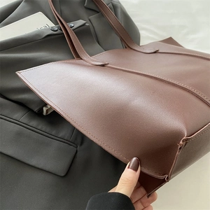 Macro side view of brown tote bag with leather texture and thin shoulder strap detailing
