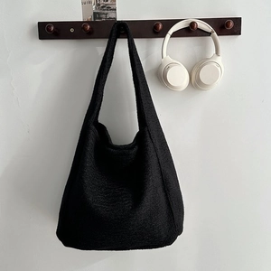 Detail des strukturierten schwarzen Bouclé-Stoffs dieser großen minimalistischen Tasche