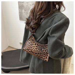 Detail of leopard print baguette bag on a model wearing a green corduroy blazer