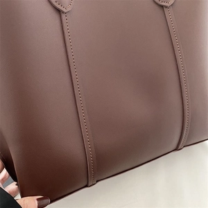 Detailed view of dark brown leather tote bag showing neat stitching and fine matte texture