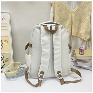 Detail view of white canvas backpack side pocket and durable brown adjustable strap