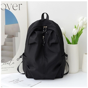 Detail of minimalist black nylon backpack showing vertical hidden zipper and side pocket