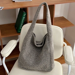 Detail einer grauen Woll-Tote-Tasche mit gewebter Textur auf weißem Sessel