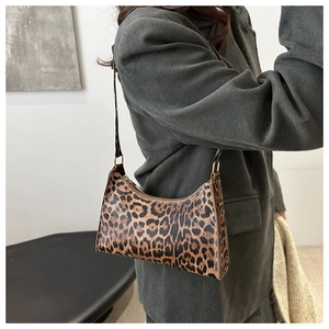 Detailed close-up of leopard print underarm bag on model with dark corduroy blazer