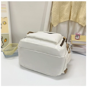 Detail view of cream casual backpack with brown zipper accents and side pocket features