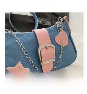 Détail du sac à bandoulière en denim bleu avec étoiles et écussons en forme de cœur roses