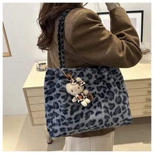 Dettaglio della borsa tote in peluche leopardata blu con manici intrecciati e ciondolo