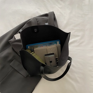 Detail shot showing the spacious interior of a black minimalist tote bag with magnetic clasp