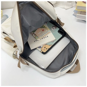 Spacious interior of off-white nylon backpack showing storage for laptop and books