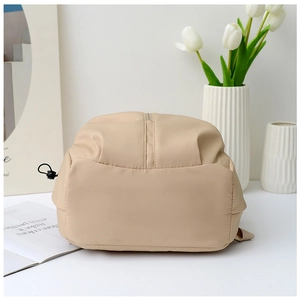 Detail view of the nylon backpack bottom with neat stitching and beige fabric texture