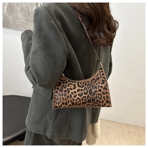 Close-up of a leopard print baguette underarm bag worn with a green corduroy blazer