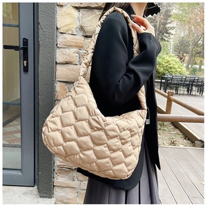 Dettaglio laterale della borsa trapuntata beige a spalla con morbida consistenza