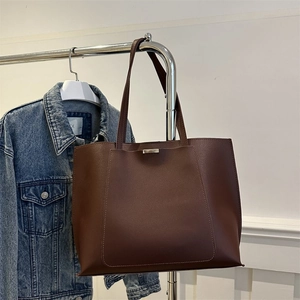 Detail of dark brown leather tote bag showing neat stitching and rectangle metal buckle