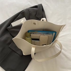 Detail shot of a large beige tote bag showing spacious interior with daily essentials