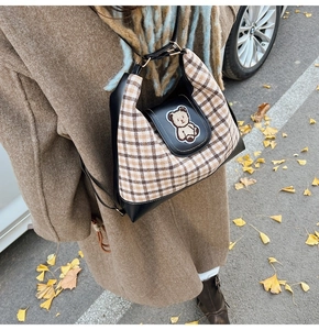 Detail of checkered autumn tote bag featuring a cute bear patch and black leather trim