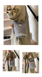 Detail van grijze wollen emmer-tas met wit label en schattige hond-pluche hanger