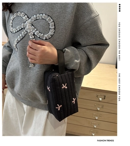 Detail of cute black quilted cosmetic bag with pink butterfly embroidery and zipper