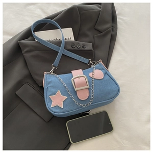 Détail du sac bandoulière en denim bleu avec étoile en cuir rose et chaîne argentée