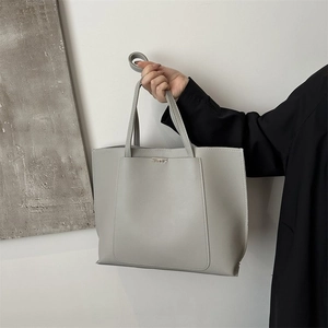 Detailed view of grey tote bag with matte leather texture and slim shoulder straps