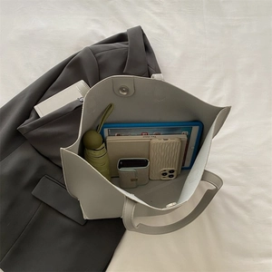 Detail showing high-capacity interior of grey PU leather tote bag with tablet and books