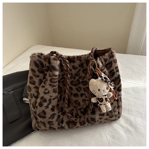 Dettaglio della borsa tote in peluche leopardata con manico intrecciato e ciondolo soffice