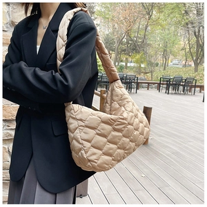 Dettaglio della borsa tote trapuntata beige con trama imbottita e tracolla larga