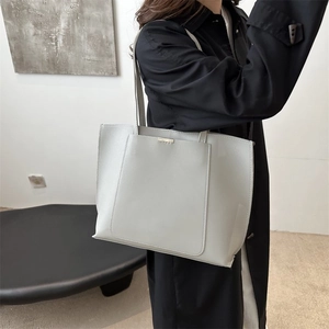Close-up of a light grey tote bag featuring a minimalist front pocket and gold metal detail