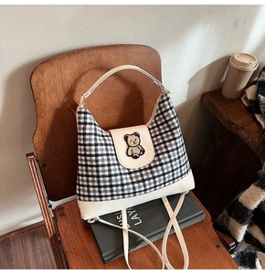 Detail of checkered canvas tote bag with bear embroidery and white leather base