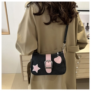 Détail du sac bandoulière en denim noir avec écusson étoile rose et boucle en métal argenté