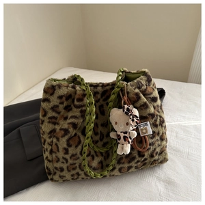 Dettaglio della borsa tote in ecopelliccia leopardata con manici verdi intrecciati e ciondolo