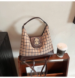 Detail of hobo tote bag featuring brown plaid fabric and teddy bear plush embroidery
