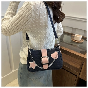 Détail d'un sac sous le bras en denim avec patchs d'étoiles roses et chaîne en métal