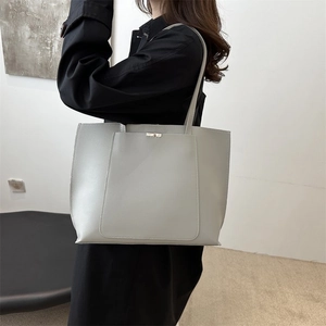 Close-up of minimalist light grey faux leather tote bag with elegant gold metal clasp