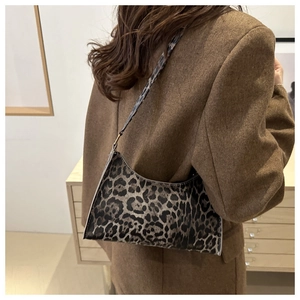 Detail of leopard print baguette bag worn with a brown blazer in a modern setting