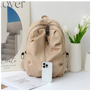Detail of minimalist beige backpack featuring front zipper pocket and side water bottle holder