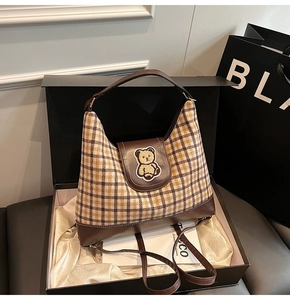 Close-up of a vintage plaid canvas tote bag with a cute bear patch in a luxury gift box